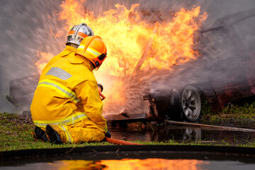 Firefighters battling a vehicle blaze during a training exercise in a rural area at dusk