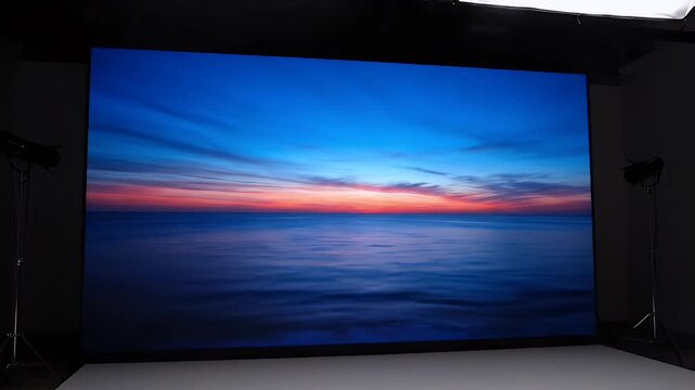 Vibrant sunset over ocean water displayed on large screen in professional studio with soft lighting
