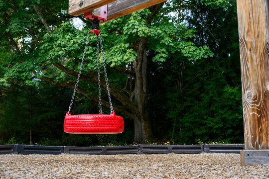 Outdoor children’s playground with new red tire swings hanging from wood supports, fun paly in the park