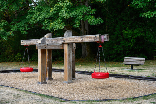 Outdoor children&rsquo;s playground with new red tire swings hanging from wood supports, fun paly in the park
