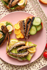 Plate of tasty sandwiches with canned smoked sprats on table