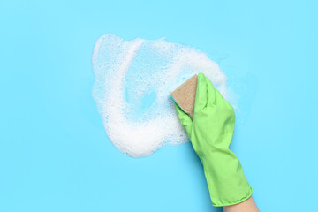 Woman with sponge and foam cleaning on blue background