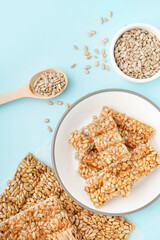 Plate with tasty kozinaki and sunflower seeds on blue background