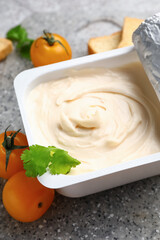 Plastic container with tasty cream cheese on table