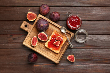 Jar of sweet fig jam and board with tasty toast on wooden background