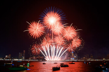 Spectacular colorful fireworks at Pattaya International Fireworks Festival 2025 viewed from a raft in the middle of Pattaya ocean. Vibrant reflections light up the dark ocean in Pattaya Bay, Thailand.