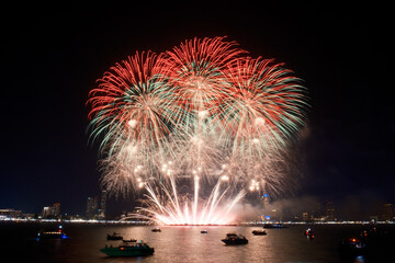 Spectacular colorful fireworks at Pattaya International Fireworks Festival 2025 viewed from a raft in the middle of Pattaya ocean. Vibrant reflections light up the dark ocean in Pattaya Bay, Thailand.