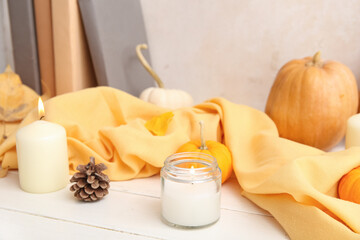 Burning candles, pine cone and scarf on white background