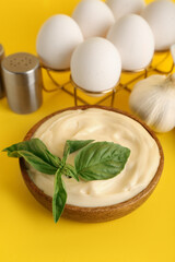 Bowl of fresh mayonnaise and ingredients on yellow background