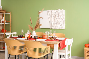 Autumn table setting with pumpkins, dry leaves and burning candles in dining room