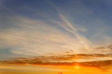 Colorful sunset sky with soft clouds and warm hues over a serene landscape seen from a distance during the late evening hours