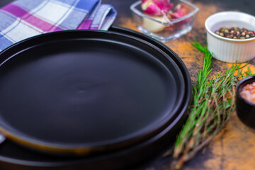 Preparing a black skillet surrounded by fresh herbs and various spices on a rustic kitchen counter for a cooking session