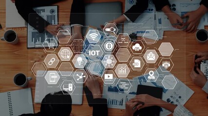 Diverse professionals collaborate in a business setting, exploring IoT solutions and data analytics, supported by digital interfaces and visual tools on the table. Raster - Powered by Adobe