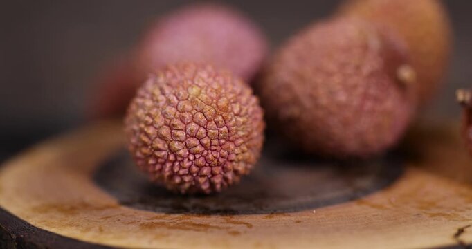 cut ripe red lychees cut into pieces on a wooden table, ripe lychee fruits with cut pink tough peel, cooking lychee