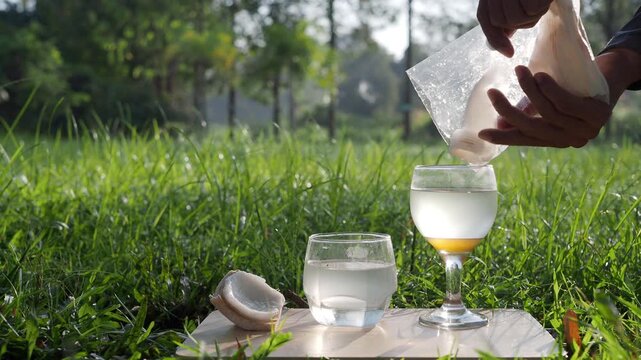 Coconut perfume water mixed with wild honey in a glass on a wooden floor in the grass.