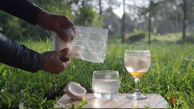 Coconut perfume water mixed with wild honey in a glass on a wooden floor in the grass.