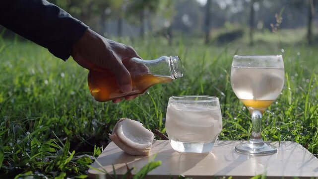 Coconut perfume water mixed with wild honey in a glass on a wooden floor in the grass.