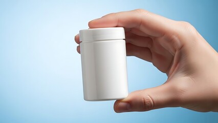 A hand holds a small, white, plastic container against a light blue background.