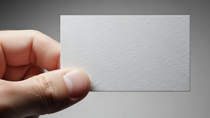 A person's hand holding a blank white business card, ready for information.
