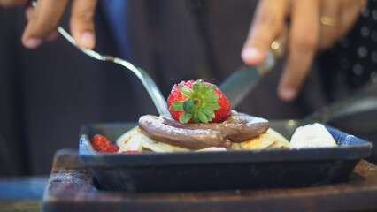 Enjoying pancake with fresh strawberries and chocolate