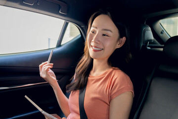 Woman sitting in a private car and hand holding digital tablet.