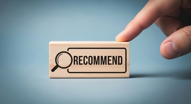 Hand pointing to wooden block with recommend text and magnifying glass icon on blue background representing suggestion concept - Powered by Adobe