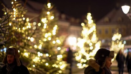 Festive city square at night with glowing Christmas trees and people walking - Powered by Adobe