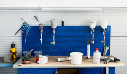 Table in car service with airbrushes for car painting, spray gun in auto repair shop