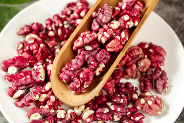 Red-Coated Walnut Kernels in Wooden Spoon - Premium Quality Nuts on White Plate