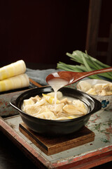 Bamboo Shoots Chicken Soup with Fresh Spring Vegetables Being Served in Traditional Black Bowl