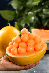 Sweet honeydew melon balls in yellow melon bowl with mint garnish - fresh summer fruit dessert