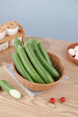 Fresh Green Loofah Gourds in Wicker Basket - Healthy Organic Vegetables on Kitchen Counter