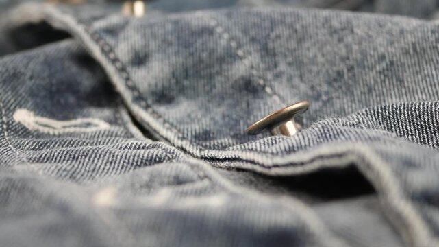 Close-up view of denim fabric and buttons during sewing
