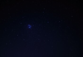 Night sky with stars and a distant galaxy.