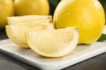 Fresh Yellow Melon Slices with Juicy Flesh and Water Droplets on White Cutting Board