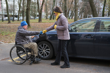 Naklejka premium A man in a wheelchair hands a woman a black box.