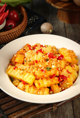 Roasted Potato Cubes with Red Peppers and Herbs in White Bowl on Rustic Wooden Table