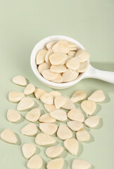 Sliced Sweet Almonds in Measuring Spoon on Green Background - Healthy Cooking Ingredient