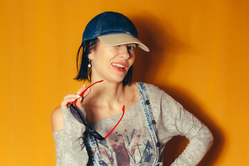 Playful woman posing with sunglasses on orange background