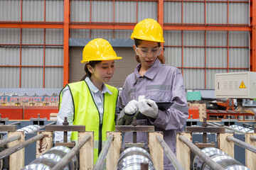 Female Engineers Inspecting Industrial Machinery in Factory inspect the quality of galvanized metal...