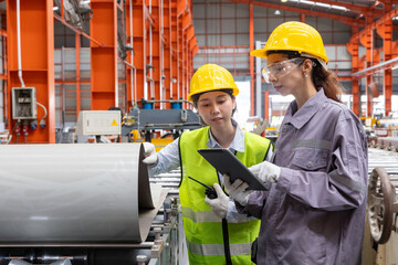Female Engineers Inspecting Industrial Machinery in Factory inspect the quality of galvanized metal...