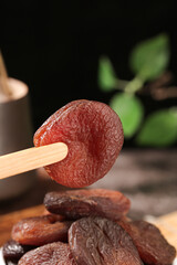 Xinjiang Dried Candied Apricots on Wooden Spoon - Traditional Chinese Preserved Fruits Against Black Background