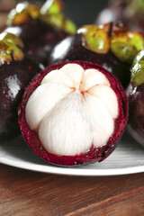Fresh Mangosteen Fruit from Thailand with White Flesh and Purple Rind on Wooden Table