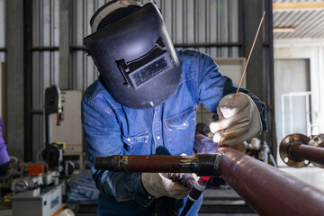 Welder performing TIG welding on metal pipe