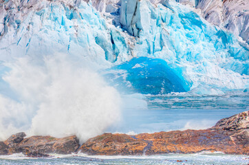 An inverted iceberg in Antarctica with a large glacier in the background - A blue glacier spinning around itself - Knud Rasmussen Glacier near Kulusuk - Greenland, East Greenland