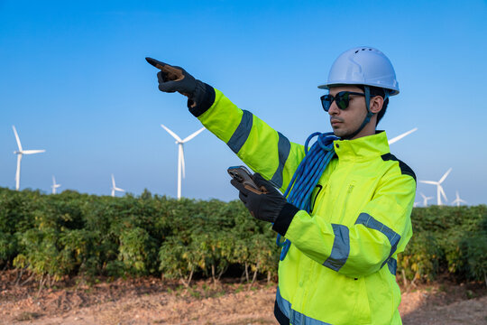 Engineer with smartphone at wind farm - Powered by Adobe