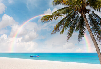 Palm trees at a tropical beach, rainbow in the background © muratart