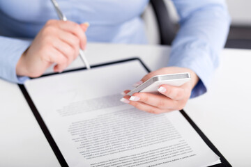 Young woman working with a mobile phone and holding a pen