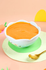 Orange Carrot Puree Baby Food in White Bowl with Gold Spoon
