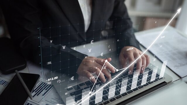 Business professional analyzes data on a laptop with digital graphs showing upward trends, reflecting market growth and financial analysis in an office environment. Copula